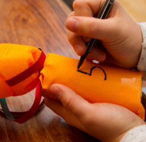 Ein Kind malt die Zahl 5 auf ein orangenes Adventsgeschenk.