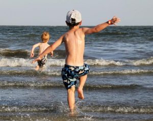 Zwei kleine Jungs laufen vom Strand ins Meer.