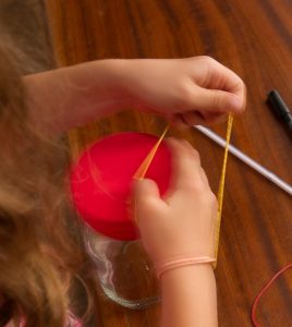 Ein Mädchen macht einen Luftballon mit einem Gummiband fest.