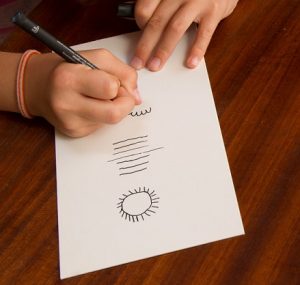 Ein Mädchen malt mit einem Eddingstift eine Skala auf ein Papier.