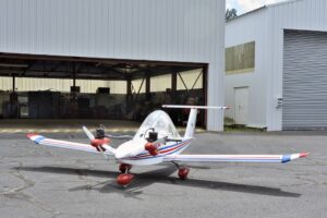 Ein sehr kleines Flugzeug vor einem Hangar. Es ist eine Cricri.