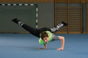 Der Junge Alex stützt sich mit beiden Händen auf den Boden. Seine Beine schweben in der Luft.