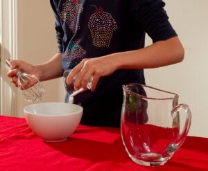 Ein Mädchen gibt Wasser in eine Schüssel.