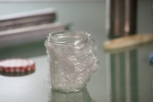 Eine Plastikfolie ist um ein Marmeladenglas gewickelt.
