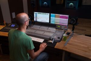 Ein Mann sitzt vor einem Misch-Pult im Tonstudio. Er heißt Andreas und ist Ton-Ingenieur.