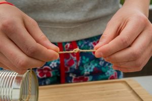 Ein Mädchen macht einen Knoten in eine Schnur.