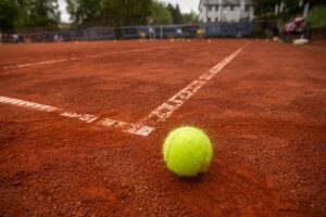 Ein Tennisball ist von sehr nahe her zu sehen. Er ist auf einem Tennisfeld in das Aus gefallen.