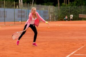 Das Mädchen Rebecca spielt einen Ball mit ihrem Tennisschläger.