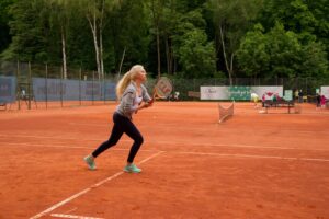 Das Mädchen Rebecca spielt eine Rückhand mit ihrem Tennisschläger.