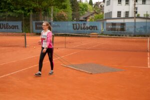 Das Mädchen Victoria macht ein Tennisfeld wieder glatt.