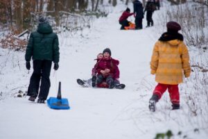 Einige Kinder rodeln einen Hang hinunter.  