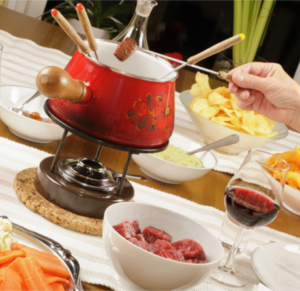 Ein Fondue-Topf auf einem Tisch mit viel Essen.