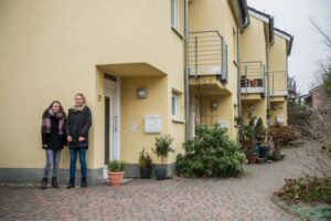 Die Mädchen Marit und Lotte stehen vor Reihenhäusern. Dort wohnen sie.