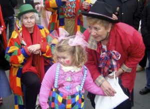Ein Mädchen und zwei alte Frauen sind zum Karneval bunt verkleidet.