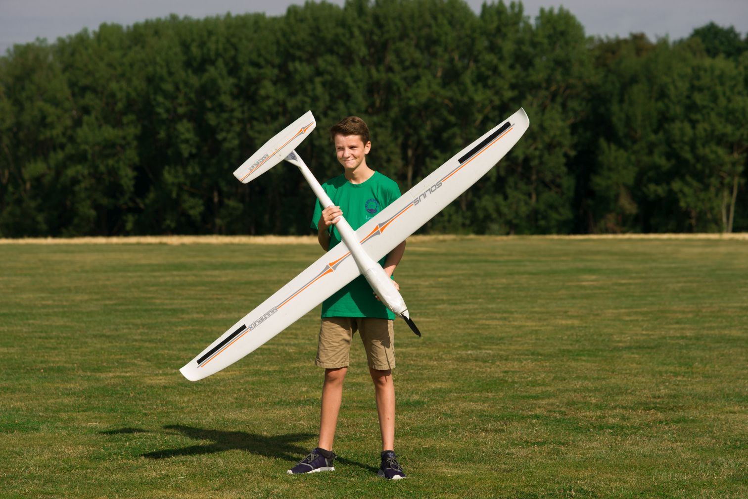 Der Junge Lenny hält einen großen Modellflieger hoch.