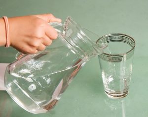 Eine Karaffe füllt Wasser in ein Glas.