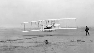 Das Flugzeug der Wright-Brothers. Es handelt sich um ein historisches Foto in schwarz-weiß.