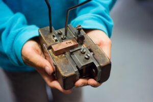 Ein Kind hält eine Form hoch. In ihr wurde ein metallener Buchstabe eingepasst. 