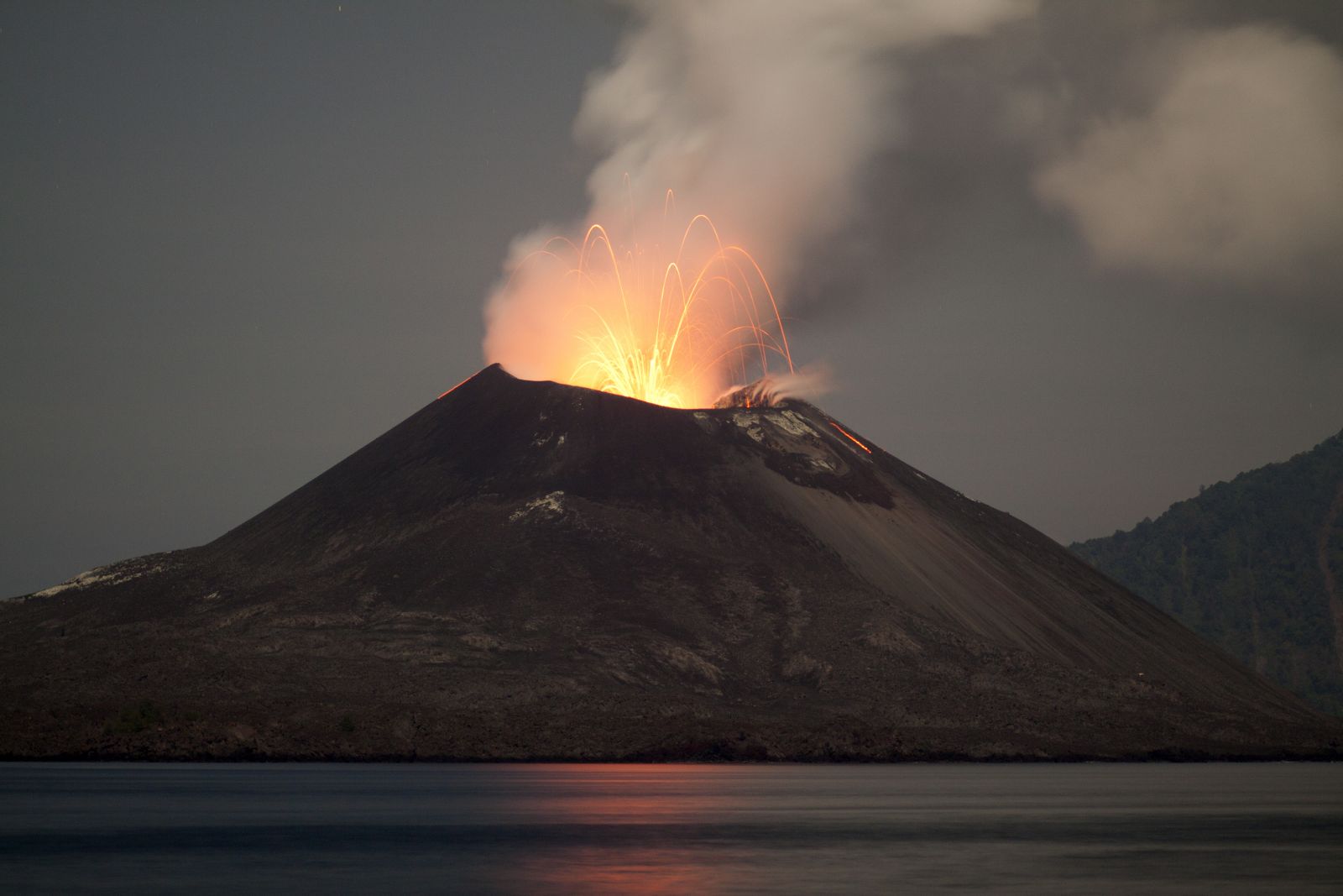 Ein Vulkan bricht aus. Rauch und Feuer steigen auf.
