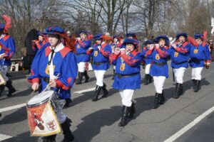 Eine blau verkleidete Musikgruppe zieht zum Karneval über die Straßen.