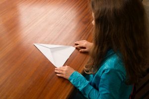 Ein Mädchen faltet die linke Hälfte von einem Blatt Papier.