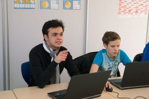 Der Junge Constantin Hamann sitzt vor einem Laptop. Er zeigt mit seinem Finger. Neben ihm sitzt ein weiterer Junge vor einem Laptop.