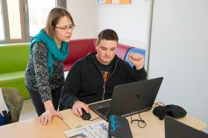 Frau Kölsch-Heck schaut gemeinsam mit einem Schüler auf einen Laptop.