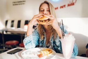 Eine junge Frau isst einen Burger. 