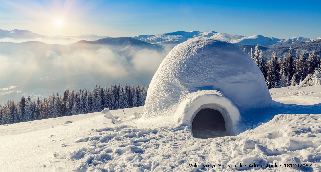 Eine Iglu Hütte auf einem verschneiten Berggipfel im Winter.