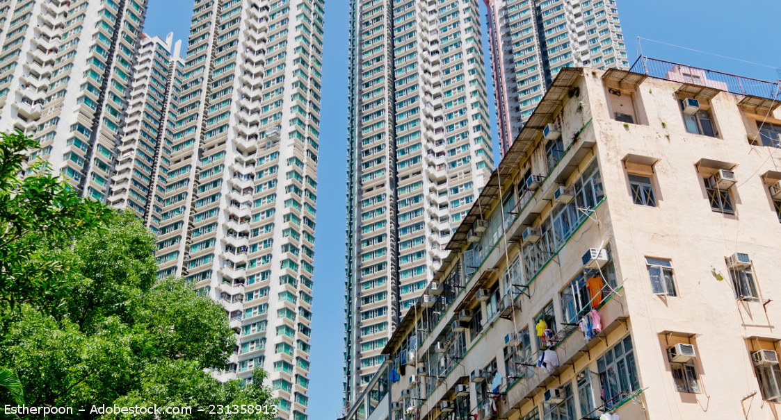 Rechts steht ein etwas herabgefallenes Mietshaus. Dahinter ragen vier Hochhäuser auf, deren Spitzen auf dem Bild nicht mehr zu sehen sind.