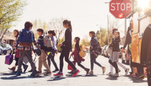 Schulkinder gehen über eine Straße.
